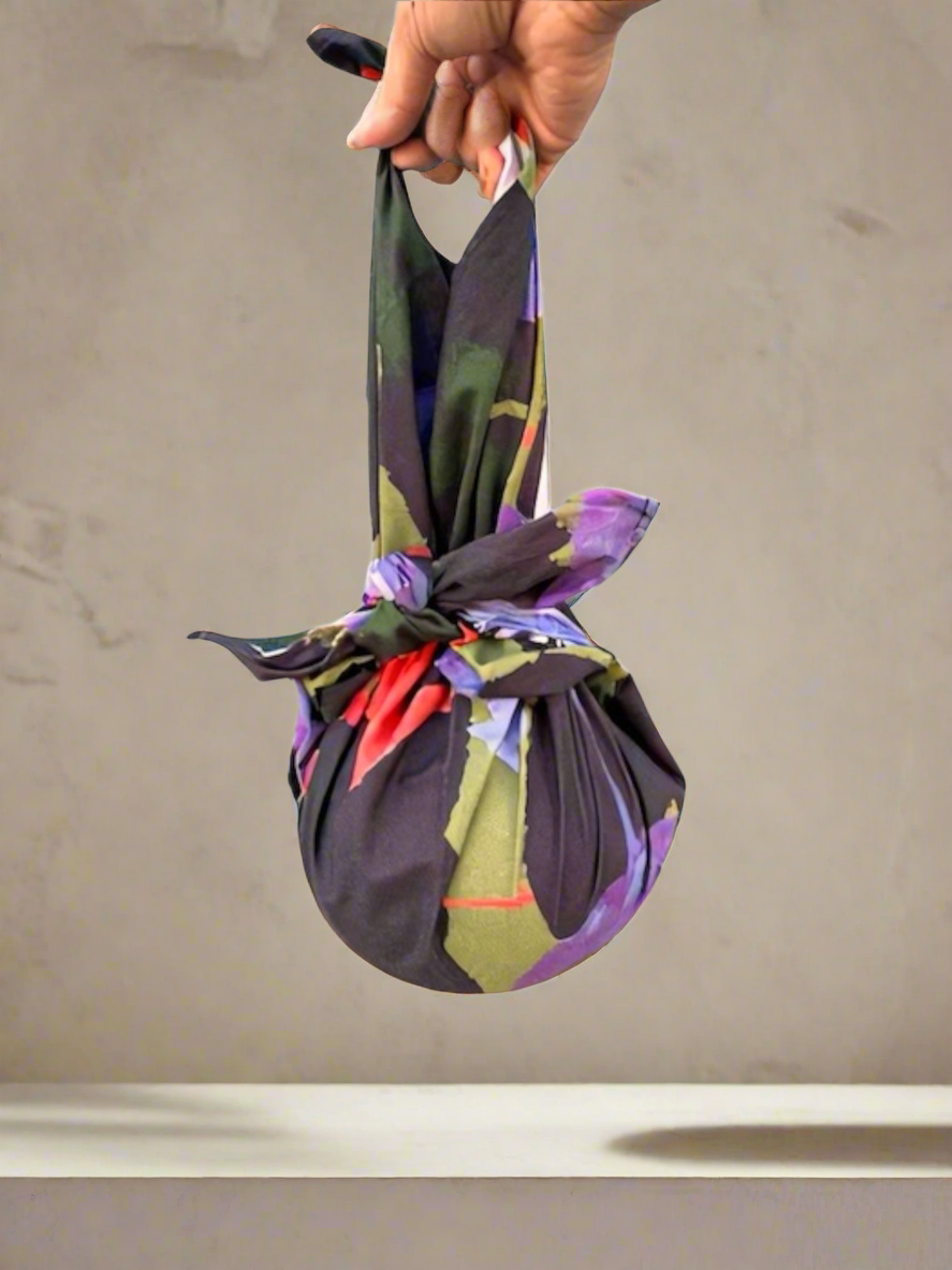 Colorful fabric bag tied in a knot held by a hand against a neutral background
