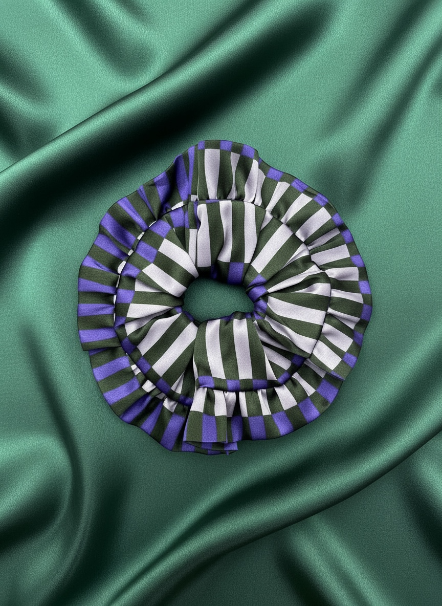 The Autumn Stripe XL Silk Scrunchie in the cool colourway  on a green satin background