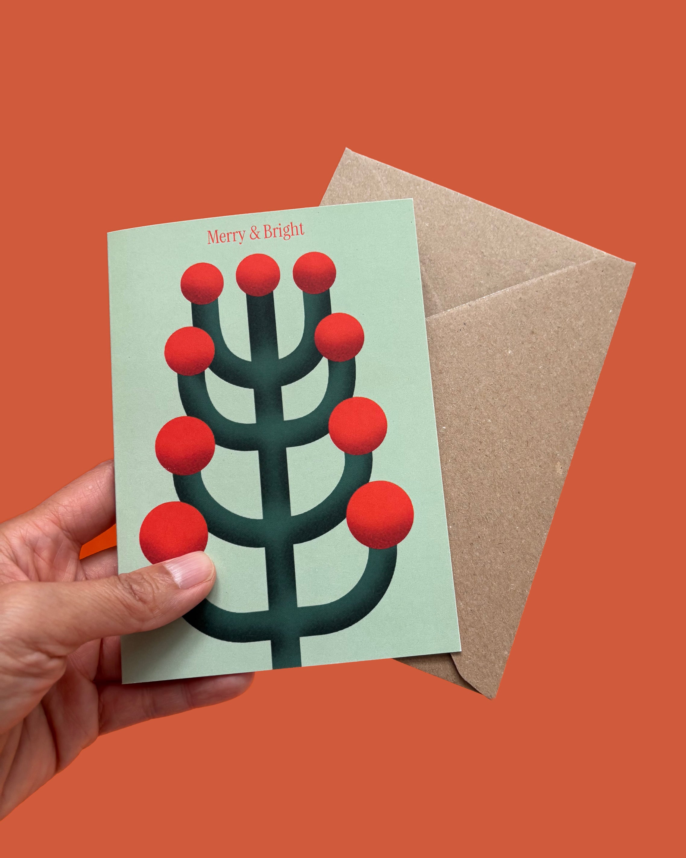 Greeting card with red and green design held by a hand on an orange background