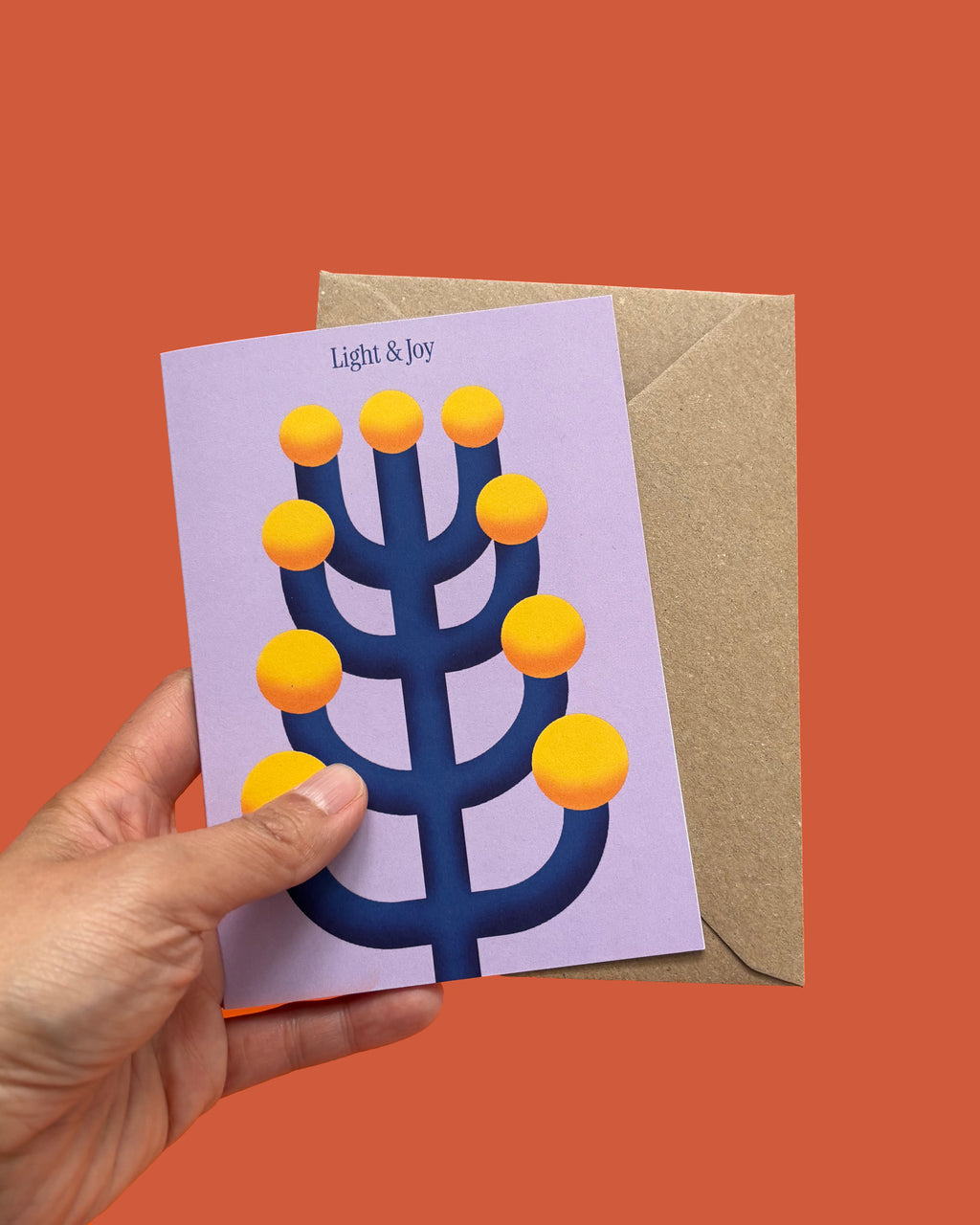 Hand holding a card with a blue menorah design on a red background
