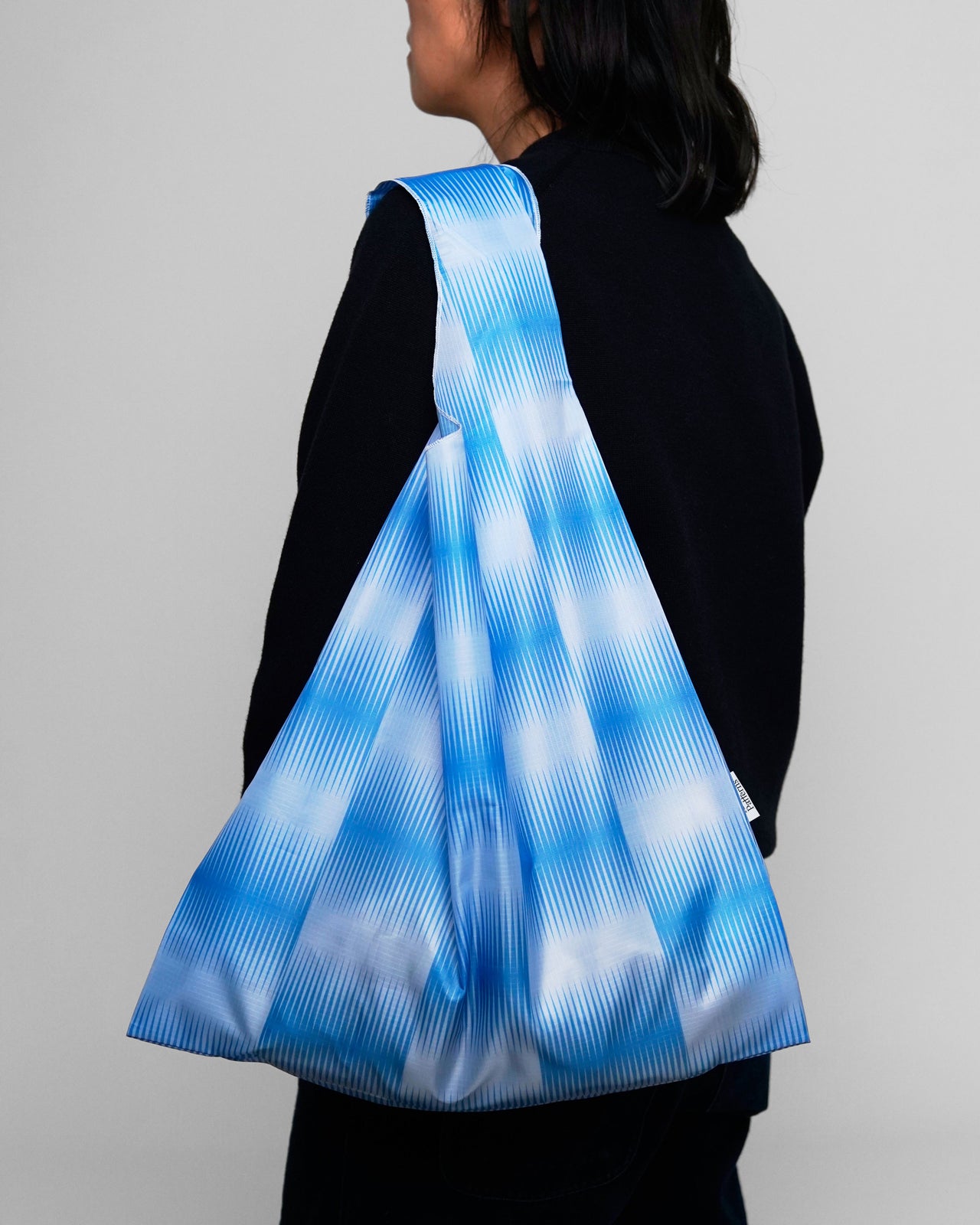 Person wearing a blue and white striped bag on a plain background