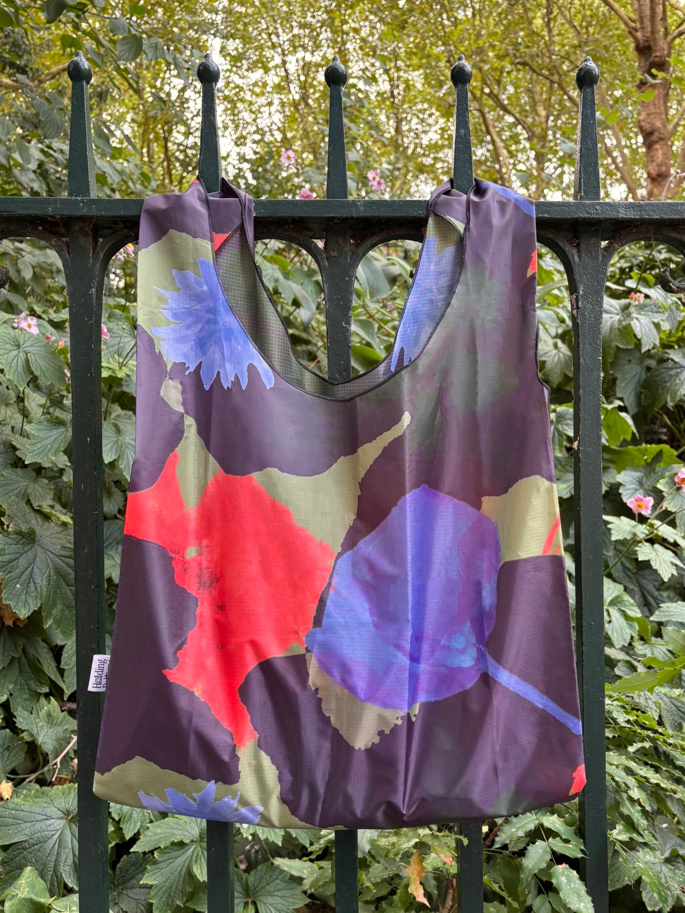 Colorful dress with abstract patterns hanging on a black metal fence.
