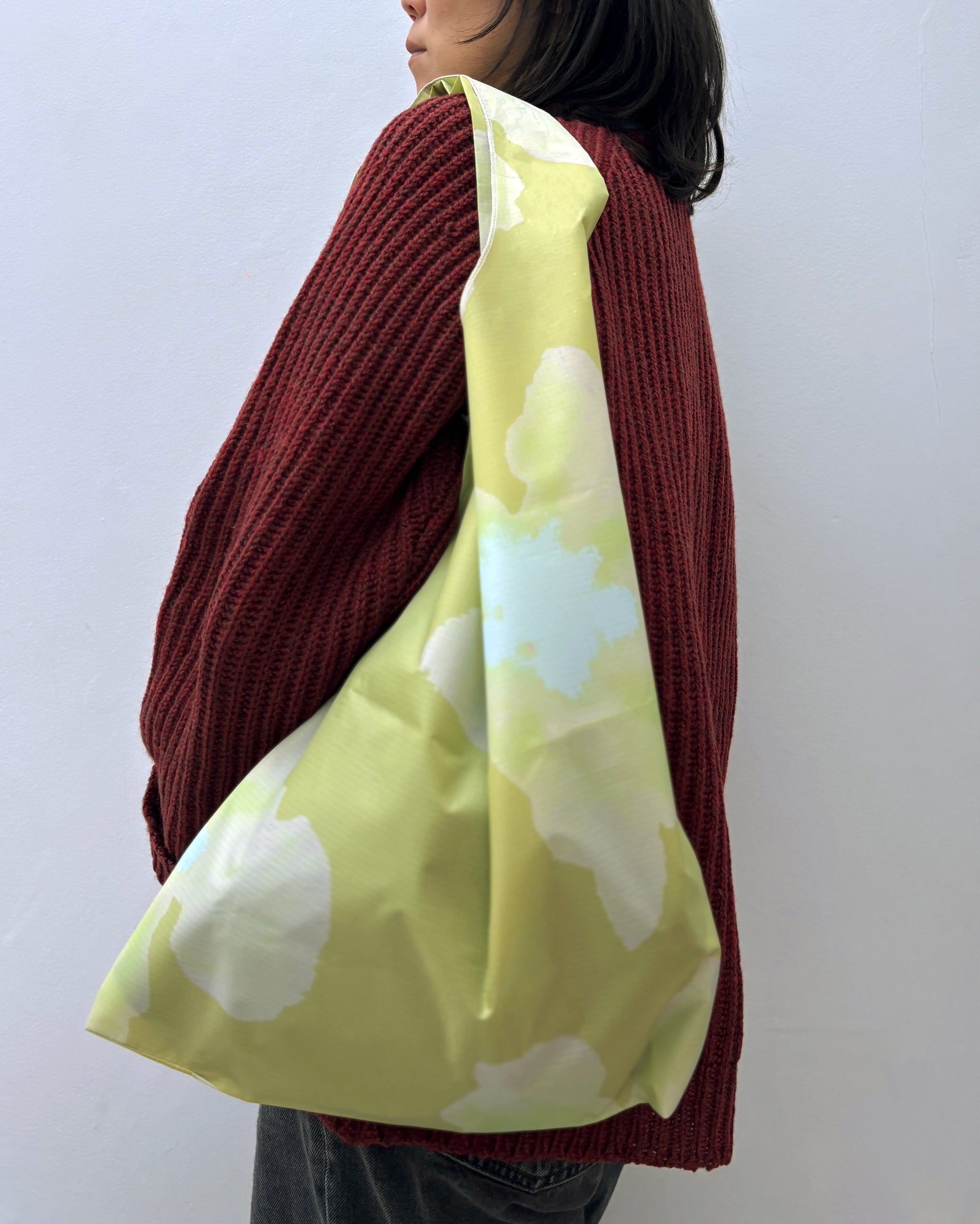 Person wearing a maroon sweater with a lemon yellow tote bag featuring white floral patterns.