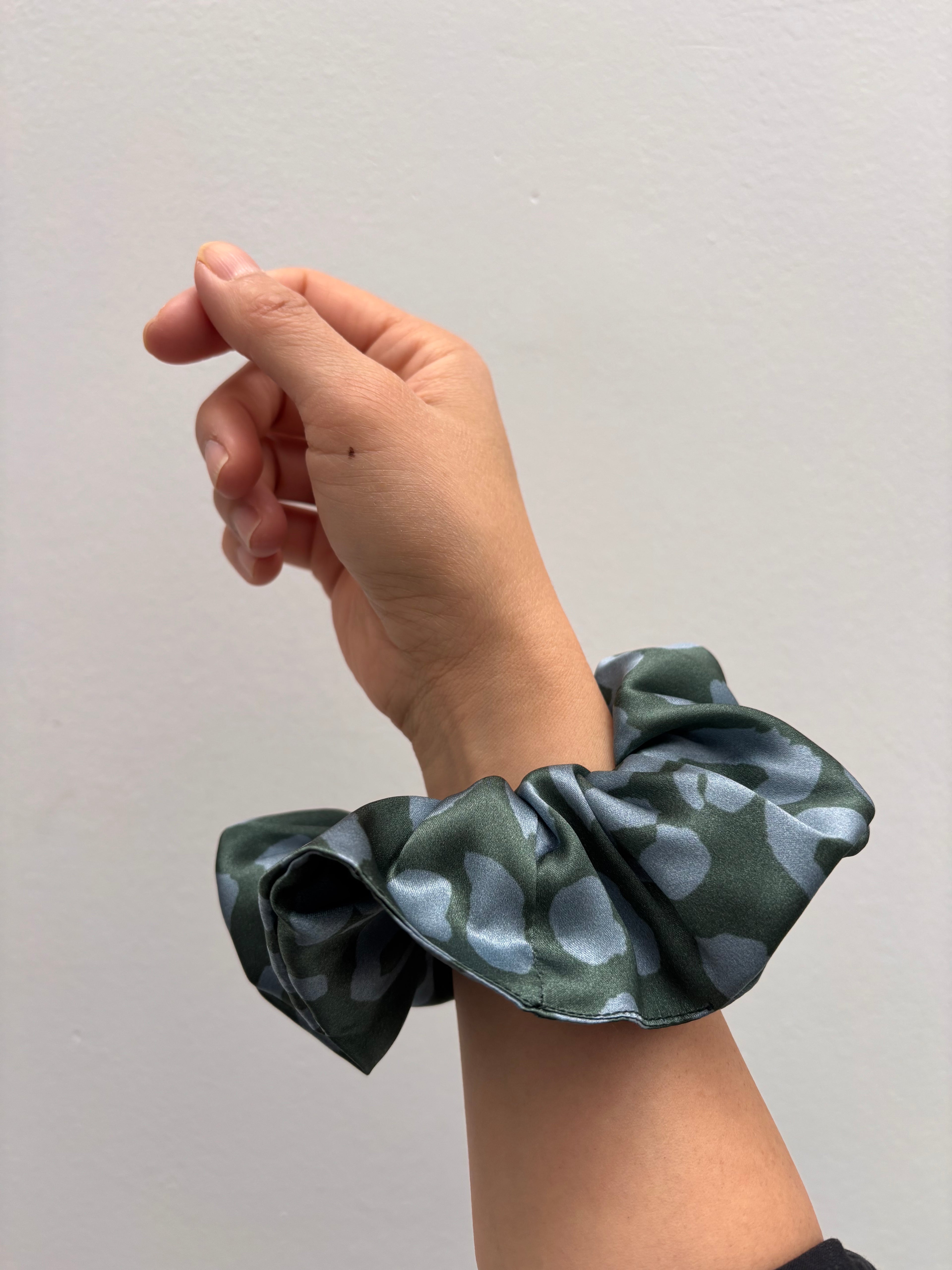 the silk hair scrunchie worn on a woman's wrist, showing the oversize scale