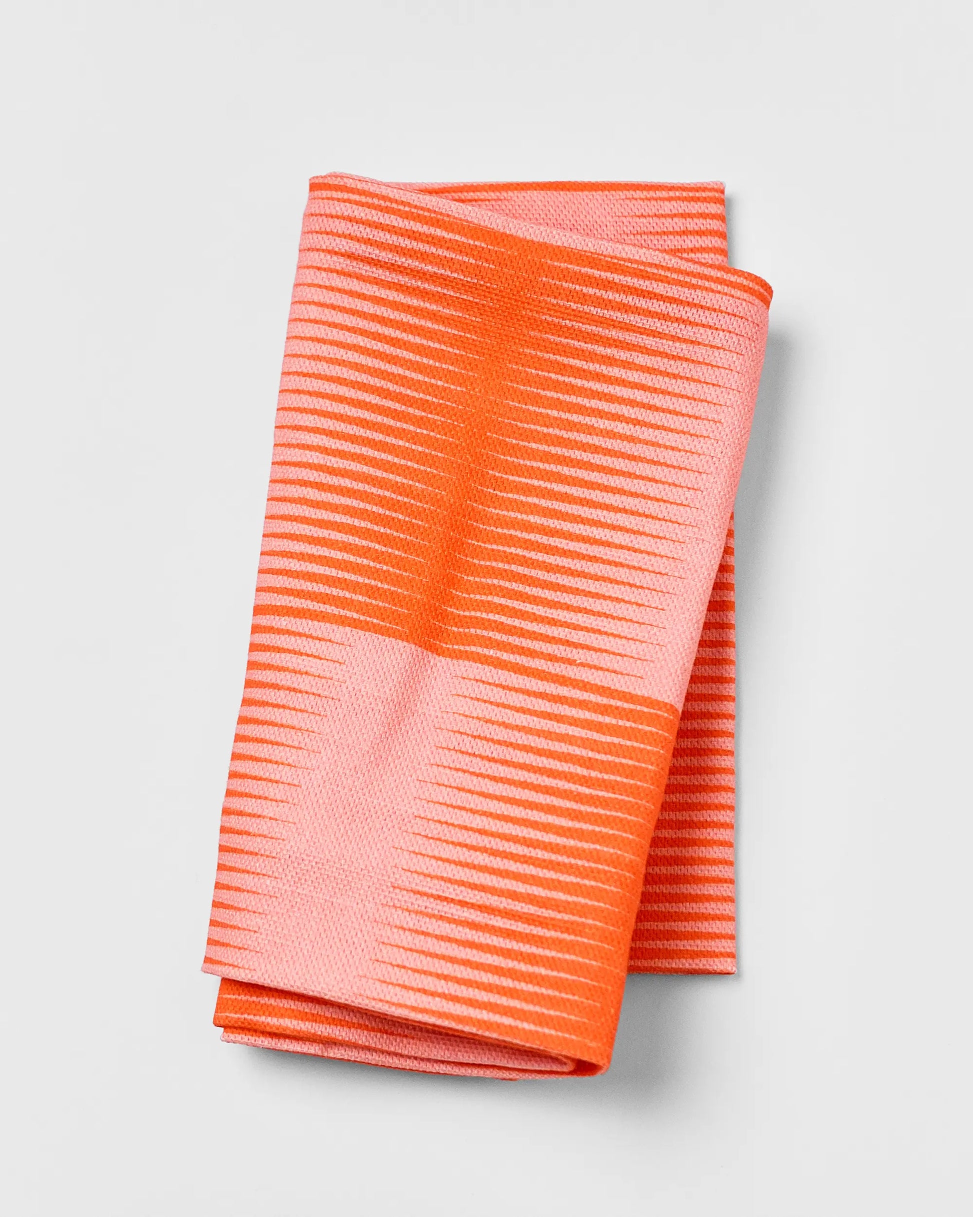 Folded orange and pink striped fabric on a light gray background