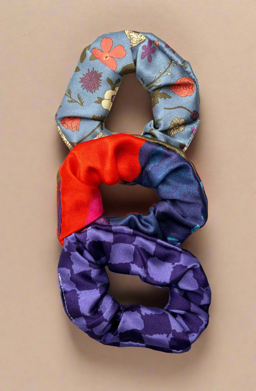 Three colorful scrunchies on a beige background