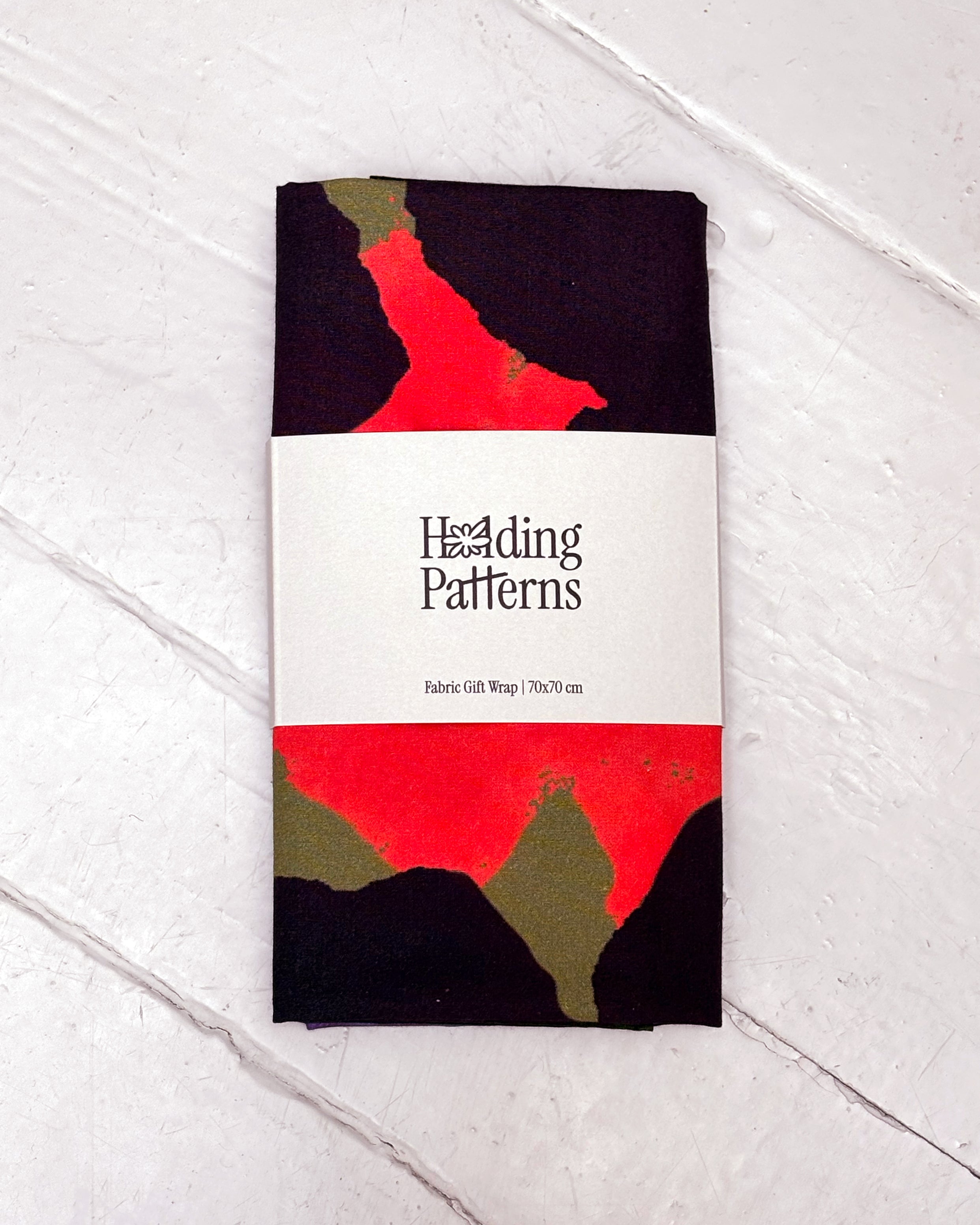 Packaged fabric with red, black, and green pattern on a white surface
