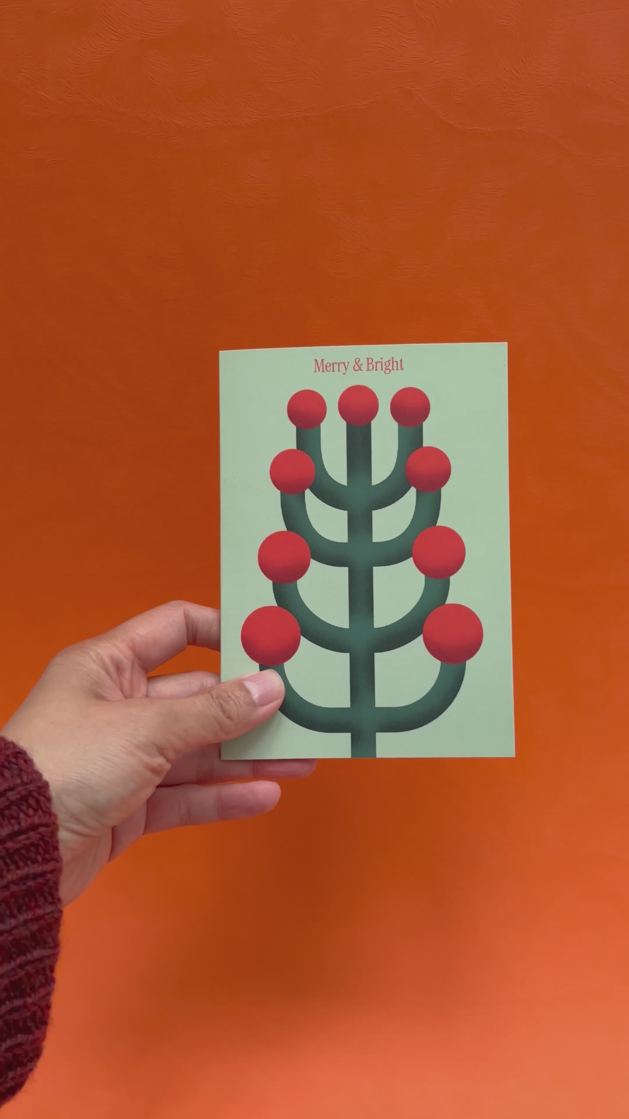 a video of hands opening a Christmas card featuring an abstracted yew motif, showing the blank interior