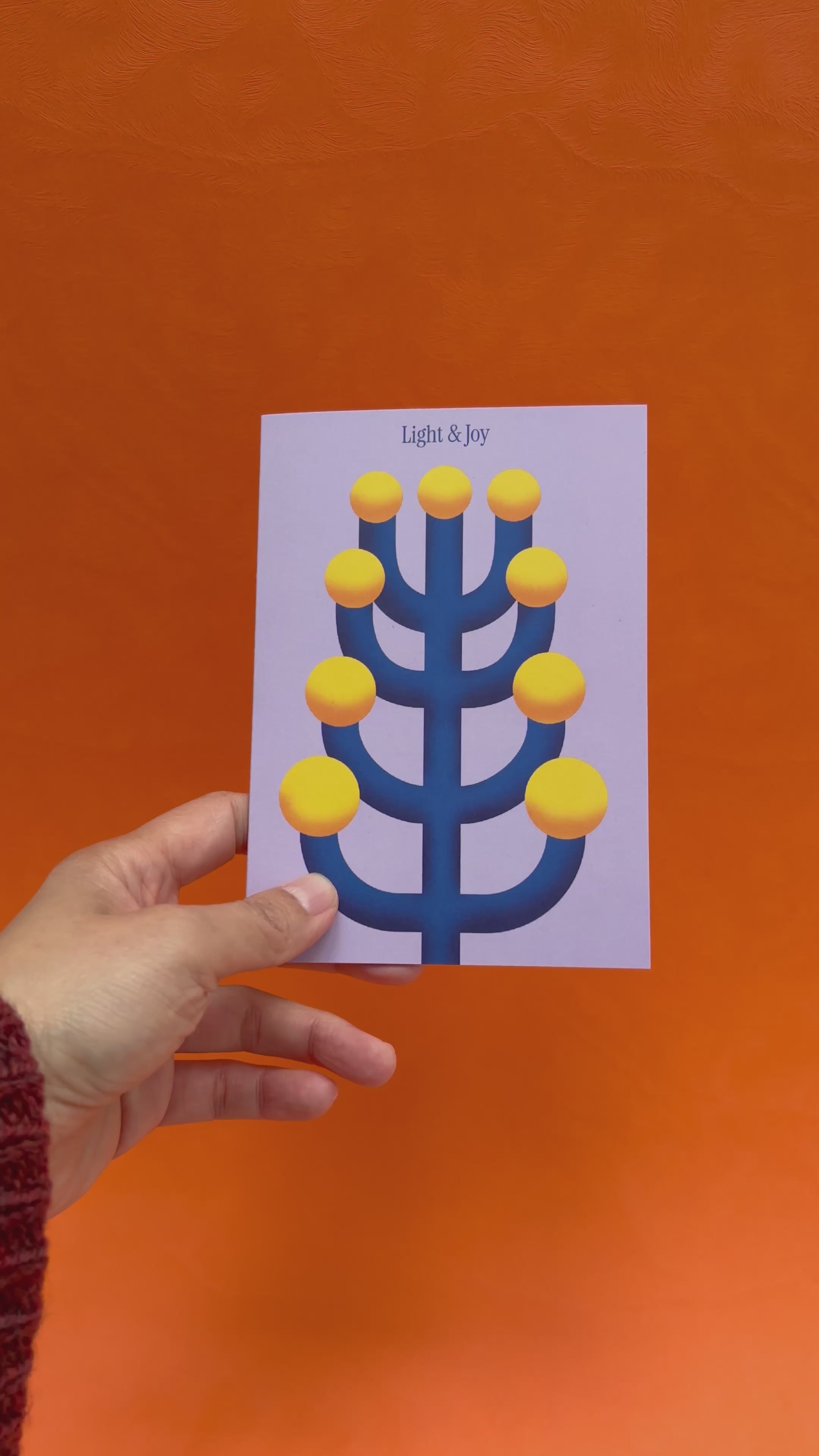 Hands opening up the festive lights greeting card, showing the blank interior and the card size